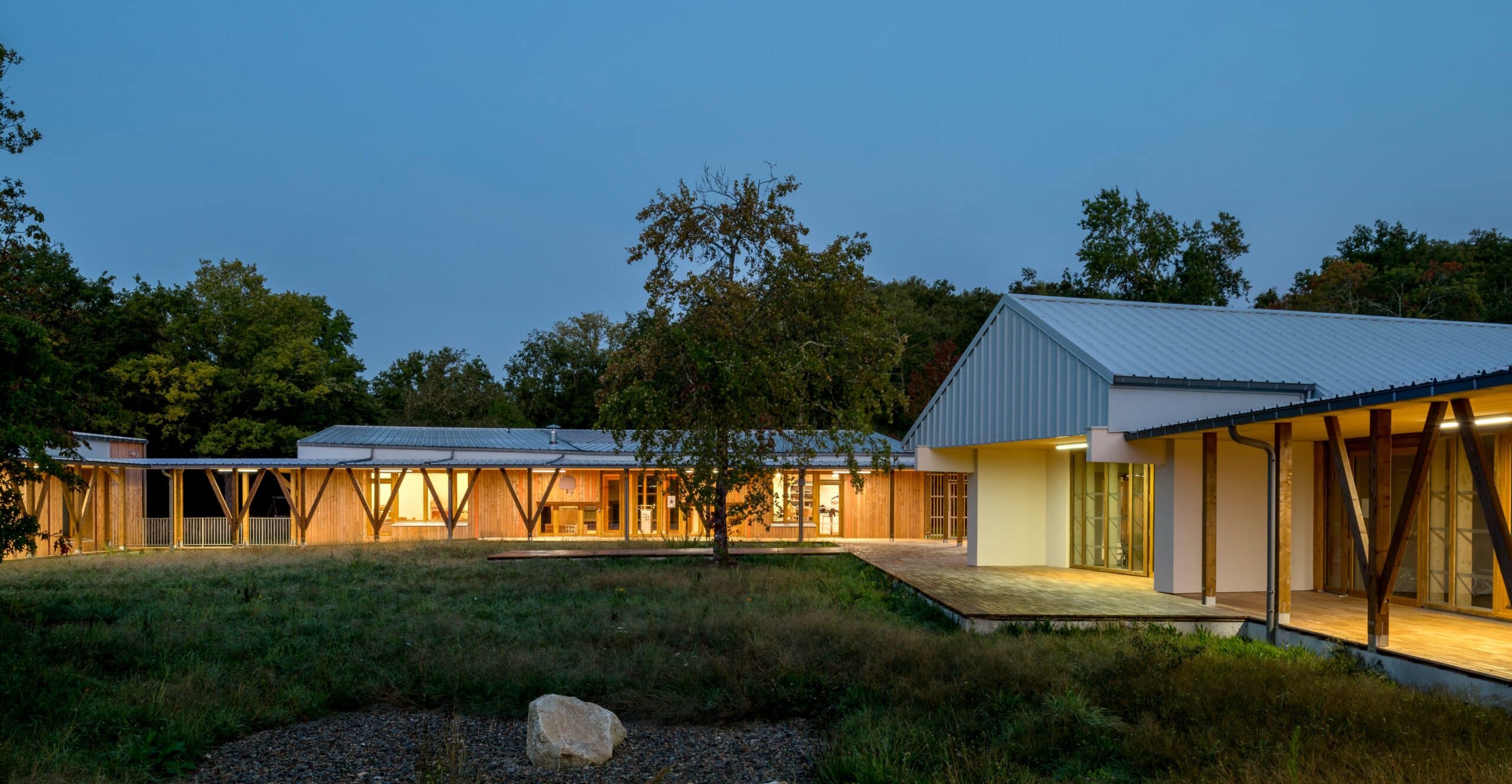 Centre de loisirs de l'Uzurat à l'heure bleue, pavillons bois-paille éclairés dans la prairie